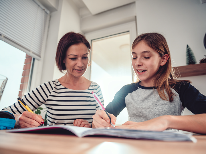 adult woman helping teenage girl with homework