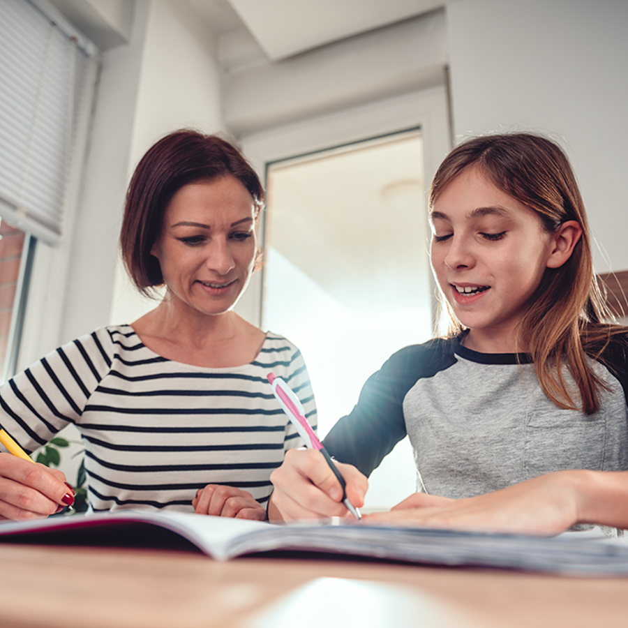 adult woman helping teenage girl with homework