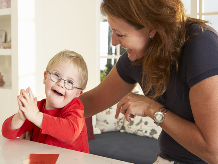 Young boy with glasses sitting next to his mum smiling and laughing