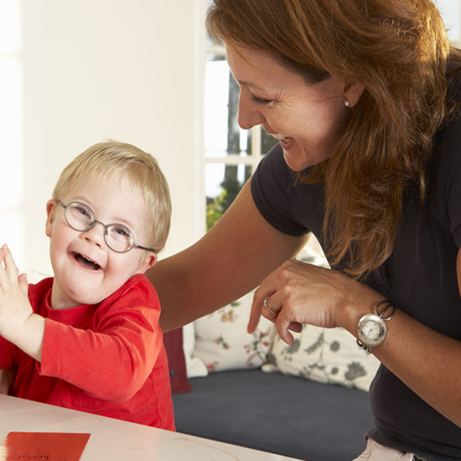 Young boy with glasses sitting next to his mum smiling and laughing