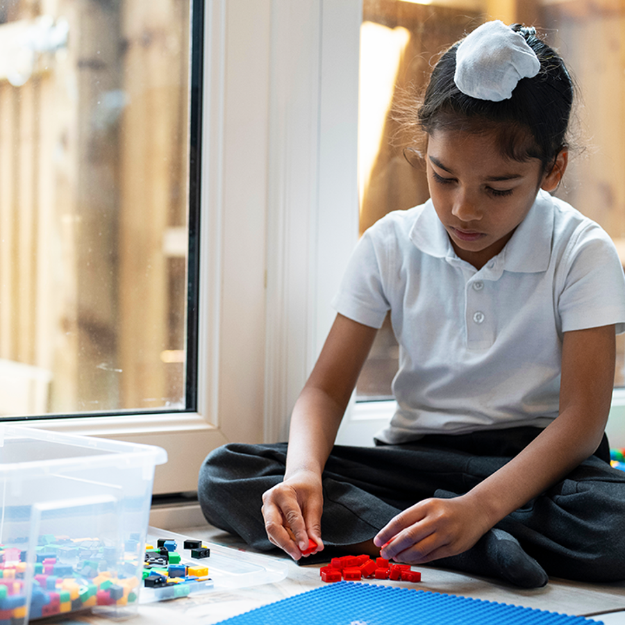 boy sitting on the floor near a glass door playing with lego