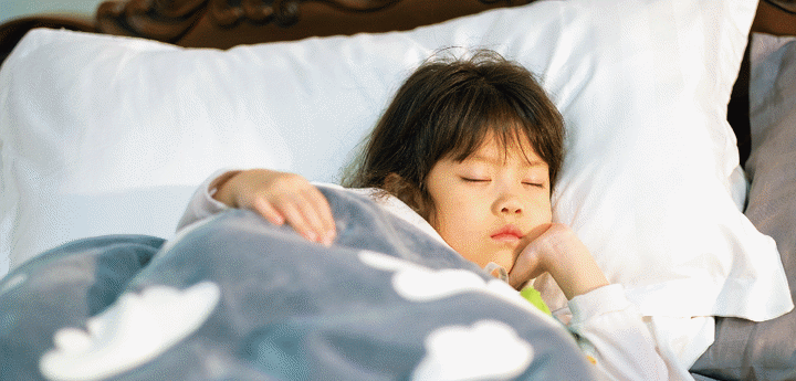 Young girl in bed with a blanket sleeping.