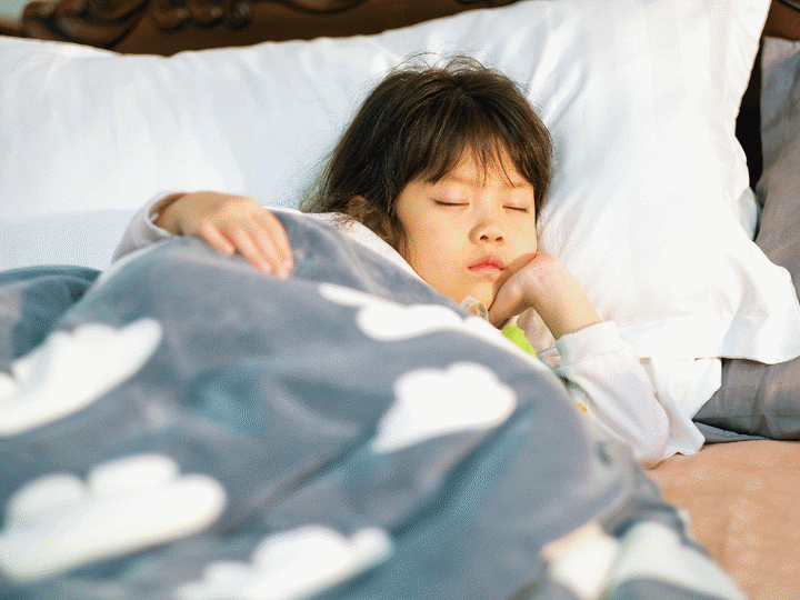 Young girl in bed with a blanket sleeping.