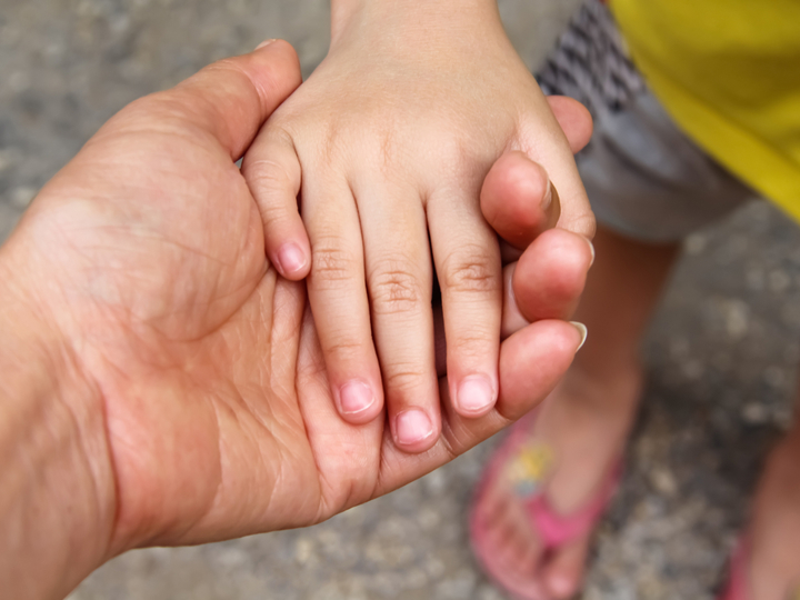 adult holding child's hand