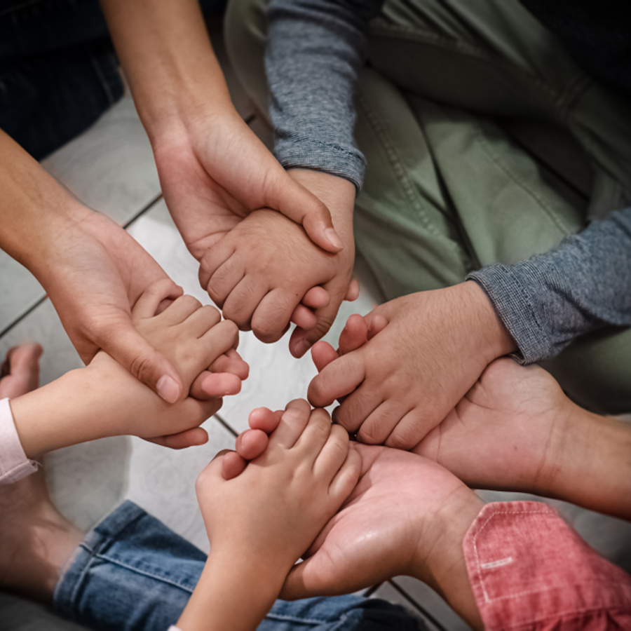 4 children all holding each others hands whilst sitting in a circle