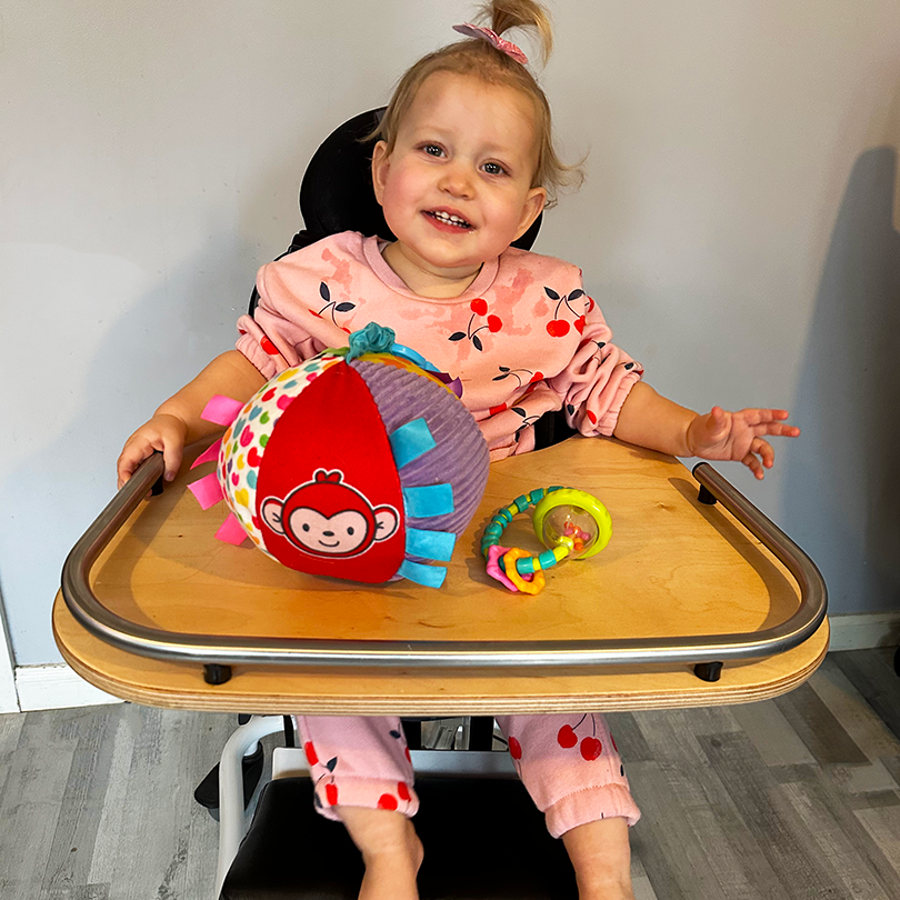 Child Sitting In Chair With Sensory Ball And Toy