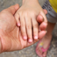 An adults hand is outstretched and a small child has placed their hand in the adults