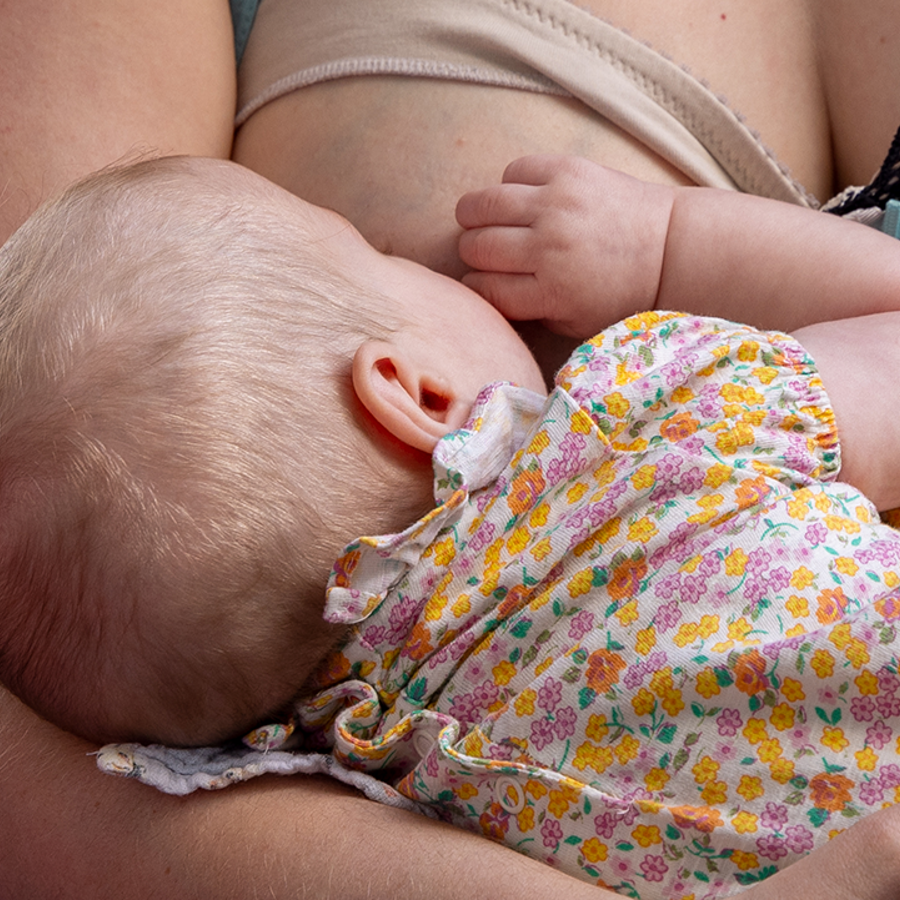 Close up of a back of a baby's head breastfeeding.