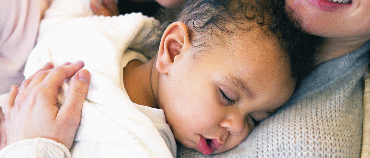 Baby sleeping face down on woman's chest.