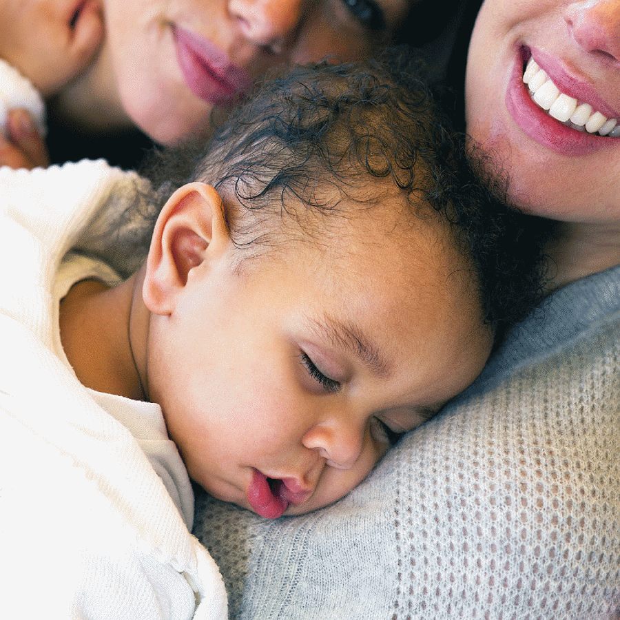 Baby sleeping face down on woman's chest.