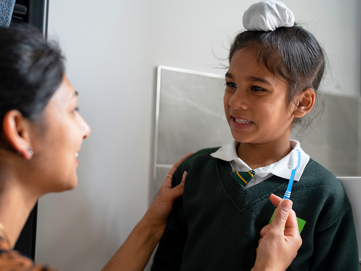 Adult holding a toothbrush checking a child's teeth.