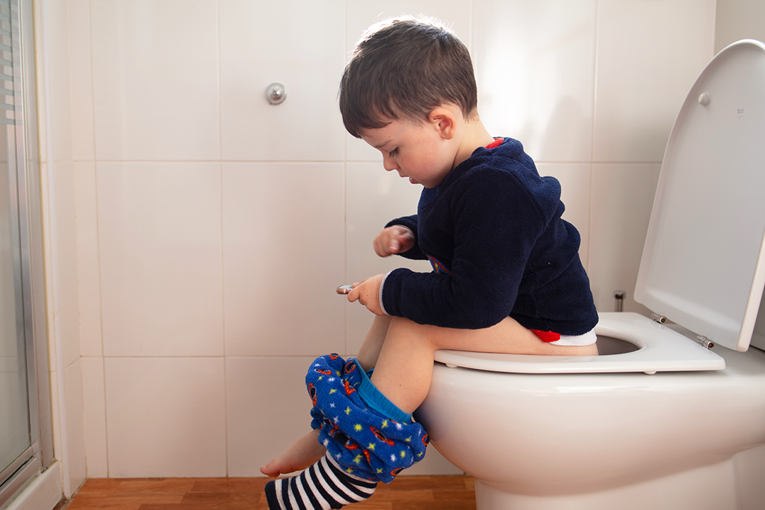 Young boy sitting on a toilet.