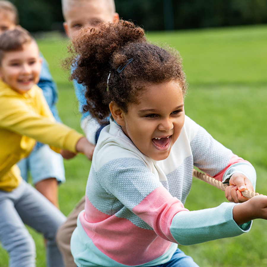 4 children playing tug of war outside in park