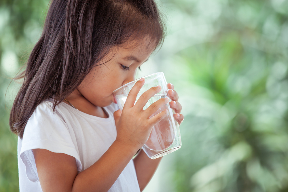 Young girl drinking from a glass of water