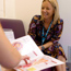 Smiling woman with NHS lanyard in background and in foreground a young person reading a booklet