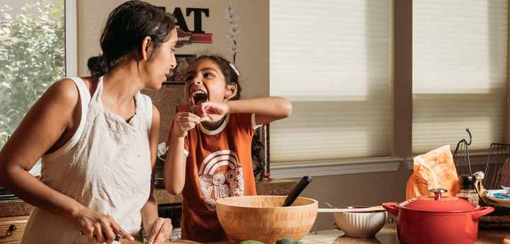 Mum and daughter preparing food while laughing together in the kitchen