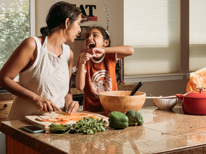 Mum and daughter preparing food while laughing together in the kitchen