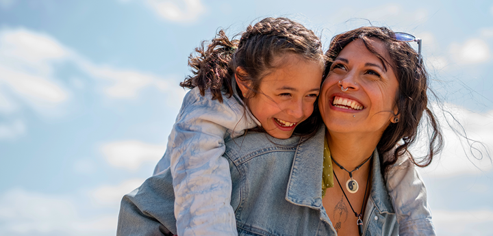 child laughing while piggybacking on an adult woman