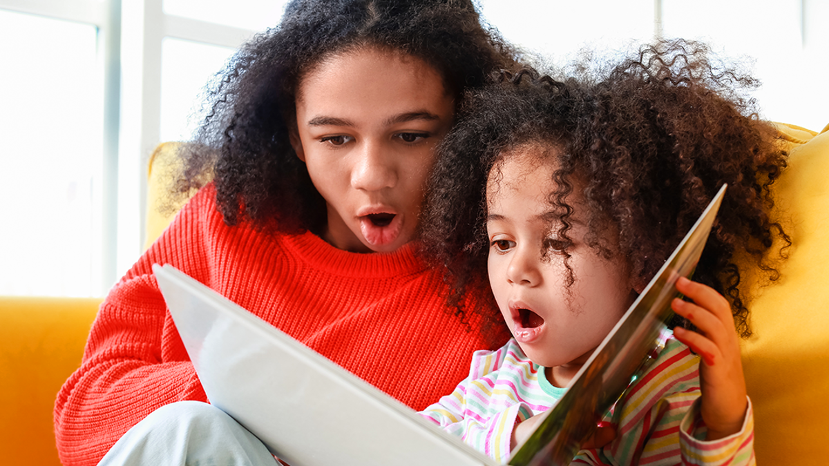 Adult and child reading book together looking shocked