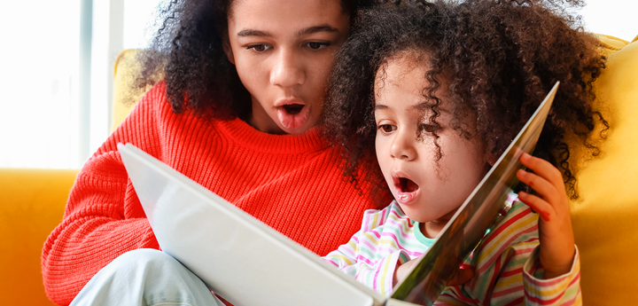 Adult and child reading book together looking shocked