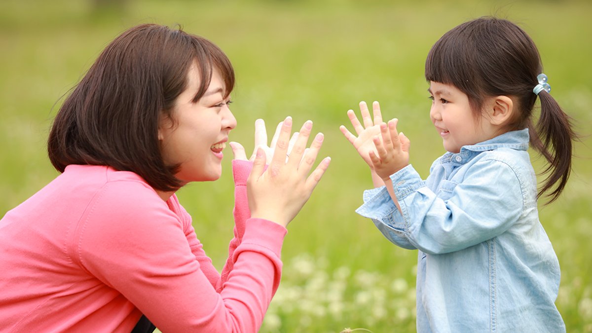 Child and adult outside clapping.