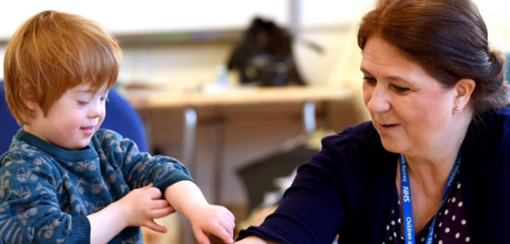 Child with Down's syndrome painting with an adult at a table