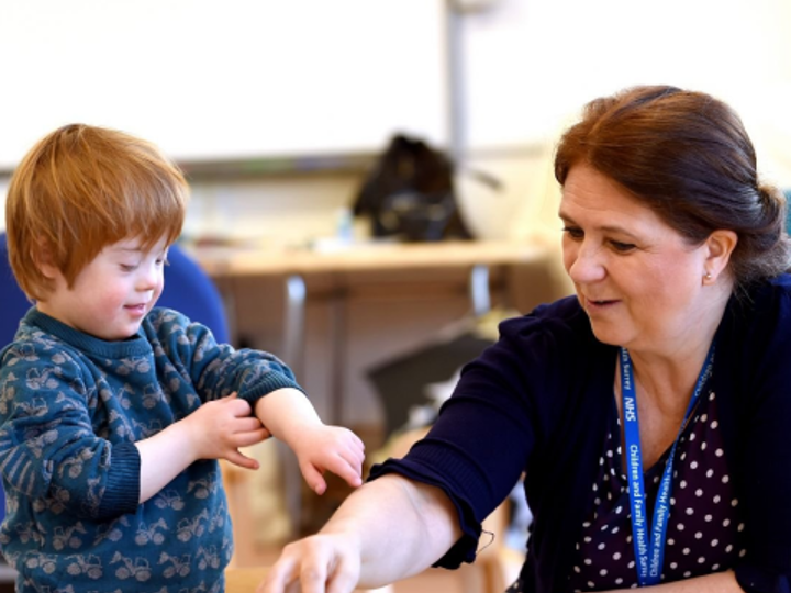 Child with Down's syndrome painting with an adult at a table