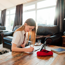 Girl sitting on the floor in a living room, doing homework on the coffee table.