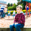 Young boy sitting on a low wall at a park