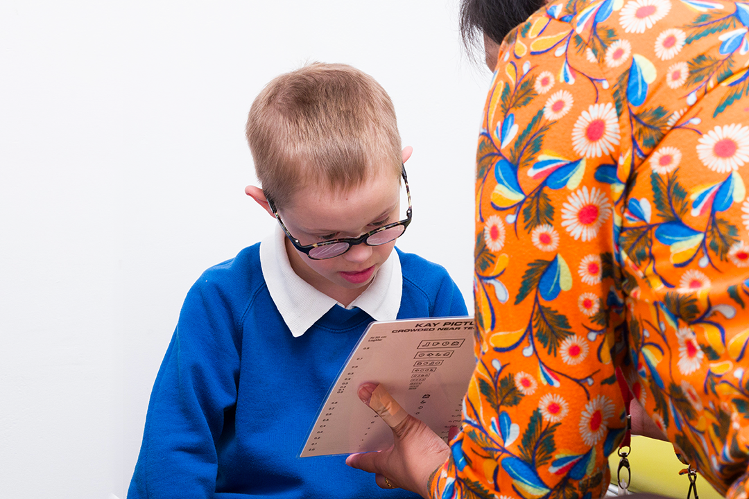 Child with Downs syndrome wearing glasses doing a eye test.