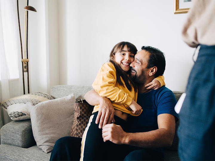 Loving Father Embracing Daughter While Sitting On Sofa At Home 1