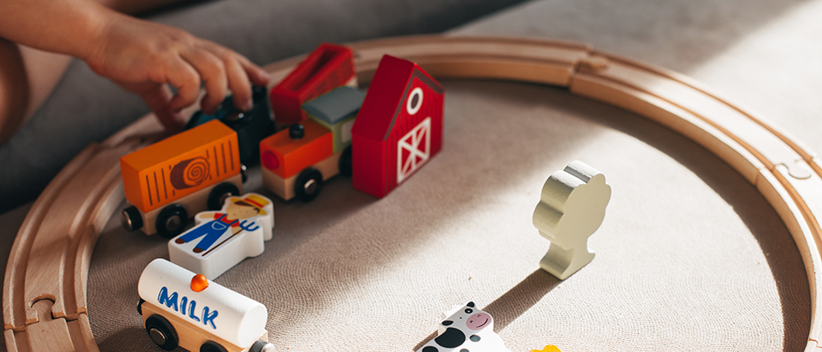 Wooden toy train on track in circle with wooden barn animals.