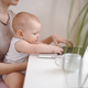 baby typing on laptop whilst sat in adult woman's lap